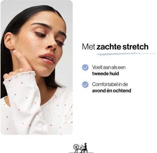 Close-up van een model die haar wang aanraakt, draagt een witte pyjamaset met rode hartjes.