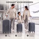 Een gezin loopt door een luchthavenhal met drie antracietkleurige koffers.