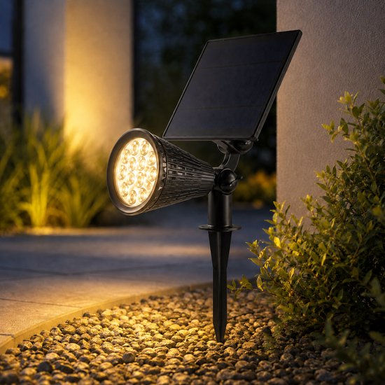 Zwarte solar spot met verstelbare koplamp, verlicht grindpad met warm licht.