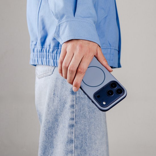 Persoon die donkerblauw hoesje met magnetische ring en telefoon vasthoudt, met blauwe jas.