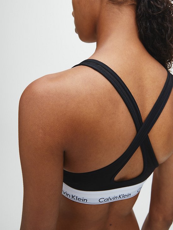 Zwarte Calvin Klein bralette met gekruiste bandjes op de rug en witte tailleband met logo.