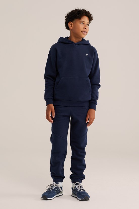 Jongen in een donkerblauwe hoodie en bijpassende broek, met witte vogelembroidery op de borst en de broek.