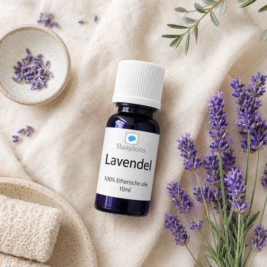 Flesje lavendelolie met witte dop, naast gedroogde lavendel en verse lavendeltakjes op linnen.