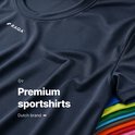 Close-up van een marineblauw sportshirt met de tekst 'Premium sportshirts' en het Raqa-logo.