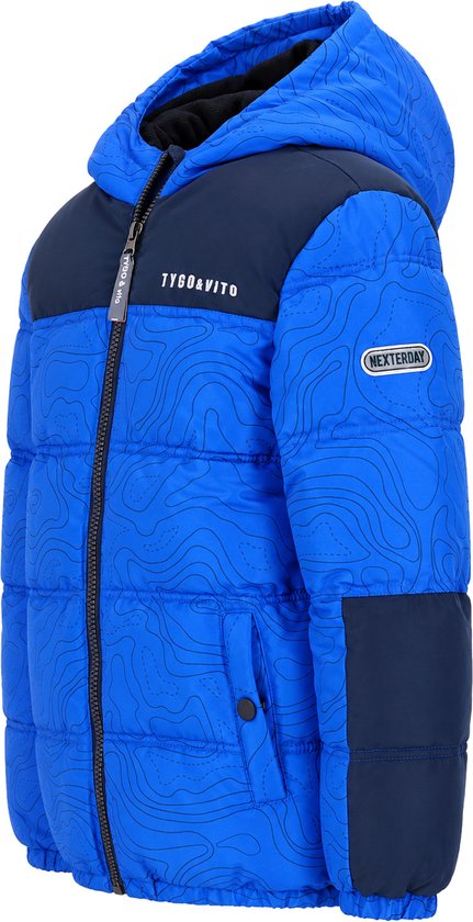 Blauw gewatteerd jongensjack met zwarte schouder- en zijpanelen. Contourpatroon, capuchon en 'NEXTERDAY' badge.