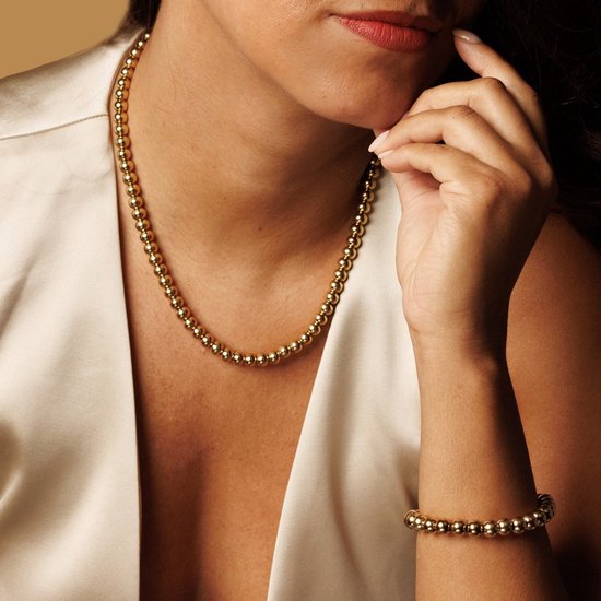 Vrouw met een gouden ketting met 7mm balletjes en een bijpassende armband.