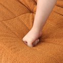Hand drukt in de zachte, oranje pluche bekleding van een zitzak.