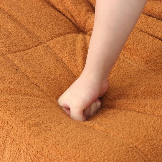 Hand drukt in de zachte, oranje pluche bekleding van een zitzak.