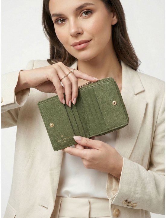 Vrouw met beige blazer houdt olijfgroene portemonnee met rits open.