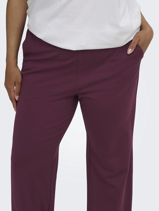 Close-up van de bordeauxrode broek met rechte pijpen en steekzakken.