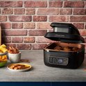Zwarte Russell Hobbs airfryer met open deksel, gevuld met aardappelen, voor gegrilde vis en salade.