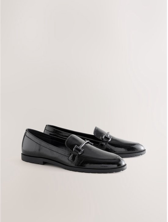 Paar zwarte glanzende loafers met zilverkleurige gespen.
