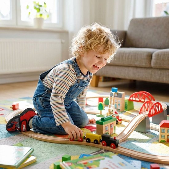 Een jongetje met krullend blond haar speelt met een houten treinset op een kleurrijk tapijt.