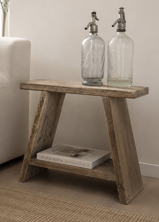 Houten bijzettafel met een plank, met twee glazen sodaflesjes en een boek erop.