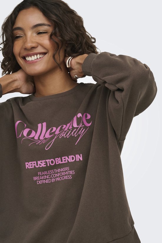 Vrouw lacht en houdt haar nek vast, draagt een bruine sweater met roze tekst.
