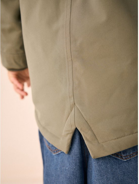 Detailopname van de zoom aan de achterkant van de groene parka met een split.