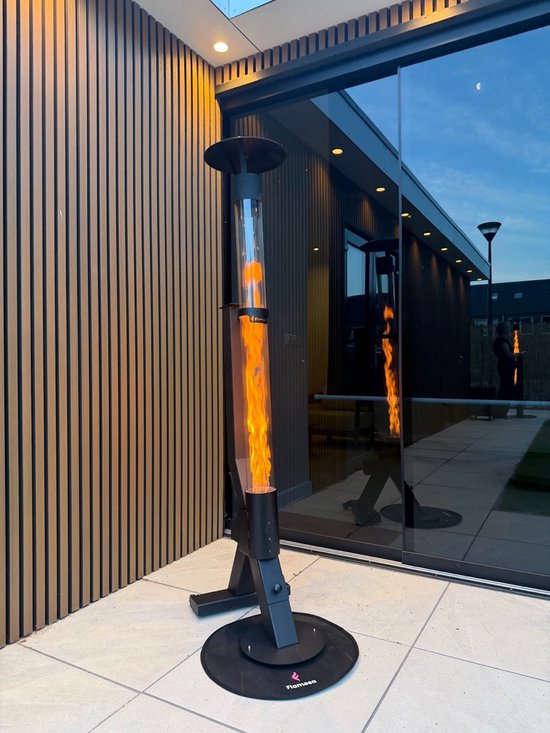 Zwarte pelletkachel met vlammen staat op een terras naast een modern gebouw met glazen pui.