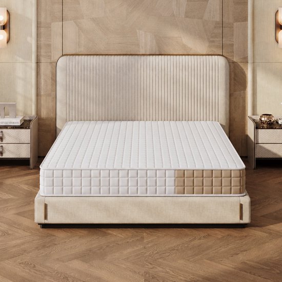 Voorzijde van een witte matras met bruin accent op een gestoffeerd beige bed.