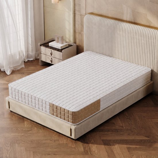 Wit matras met bruine ruitvormige accenten, op een bed in een slaapkamer met houten vloer en zachte verlichting.