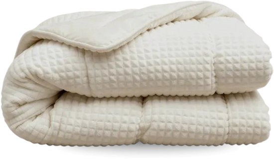 Opgevouwen crème kleurig dekbed met een zichtbaar ruit- en ribbelpatroon, in een transparante verpakking.