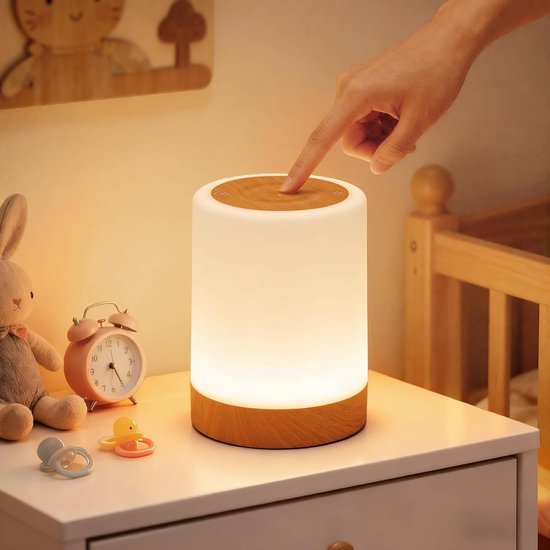 Veilleuse cylindrique avec base et dessus en bois. Une main touche le dessus.