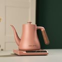 Roze waterkoker met houten handvat, staat op een roze basis met digitaal display.