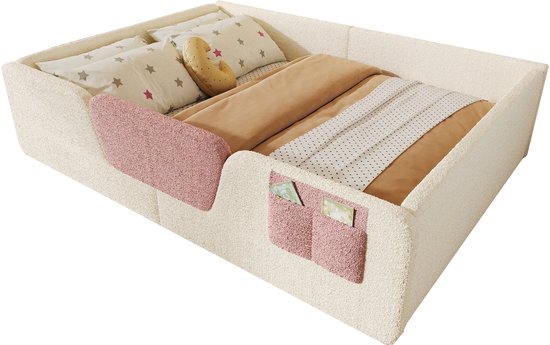 Laag kinderbed van lichtbeige teddy stof met roze opbergvakjes, opgemaakt met beddengoed.