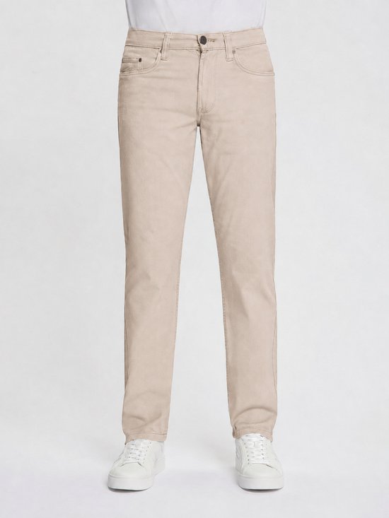 Man in beige broek, voorkant zichtbaar. Strakke pasvorm, met knoop en ritssluiting.