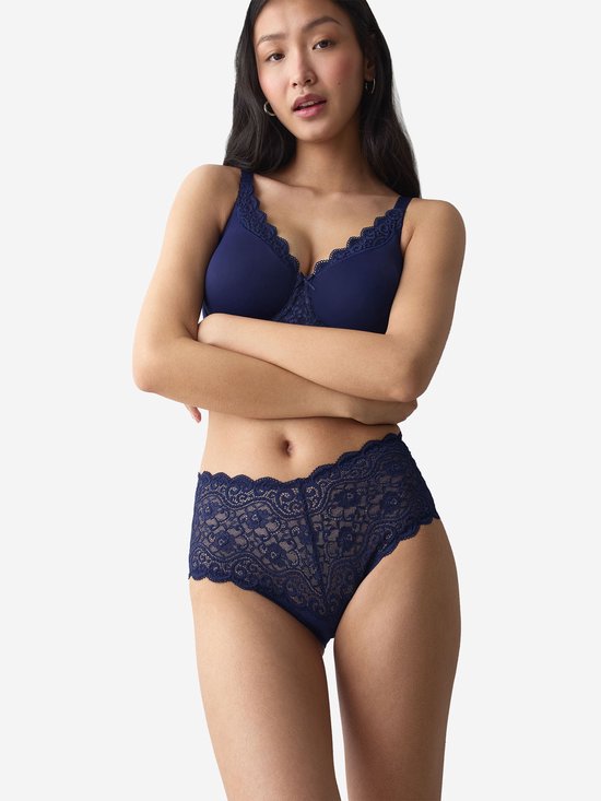 Model draagt een marineblauwe beha en slip met kanten details en kanten randen.