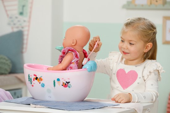Meisje met hartjes trui laat een pop in een roze, verlicht badje met douche spelen.