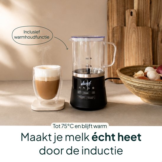 Zwarte melkopschuimer met glazen kan, inclusief warmhoudfunctie, naast een glas met cappuccino.