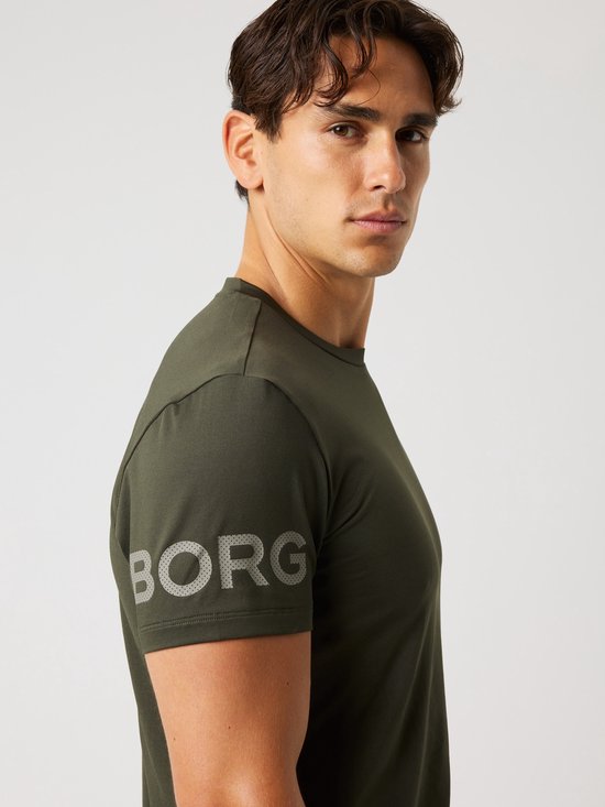 Close-up van een man die een donkergroen sportshirt draagt, met grijze 'BORG' opdruk op de mouw.