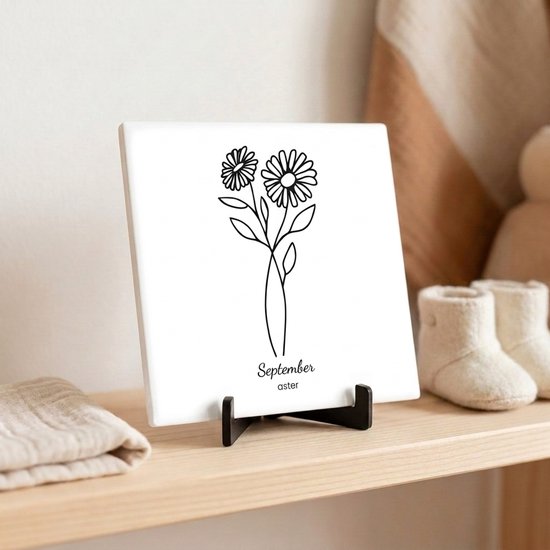 Carreau avec une illustration de l'aster, la fleur de naissance de septembre. Dessin au trait noir et blanc sur céramique blanche avec un support noir.