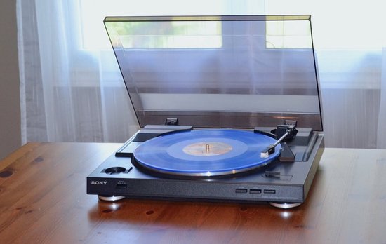 Zwarte Sony platenspeler met blauwe plaat, op houten tafel.