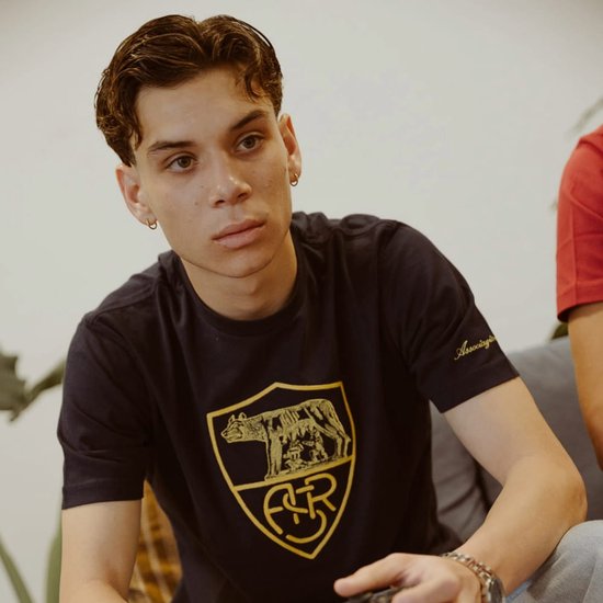 Man zit in een T-shirt met het AS Roma wapenschild, de tekst 'Associazione Sportiva' is zichtbaar op de mouw.