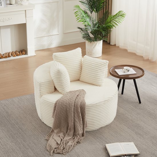 Crèmekleurige, ronde corduroy fauteuil met ribbels en drie kussens, met een plaid.