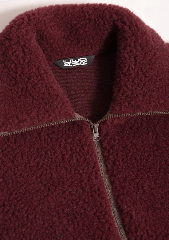 Detailopname van een bordeauxrood wollen bodywarmer met ritssluiting en een 'Alwero' neklabel.