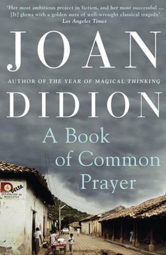 Boek 'A Book of Common Prayer' van Joan Didion. De cover toont een straatscène met een bord waarop 'Delta' staat.