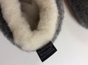 Detail van de binnenkant van grijze wollen sloffen met witte vacht en Woolmark label.