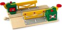 Houten magnetische treinbaanovergang van BRIO met twee groen-gele slagbomen, een rode bedieningsknop en een wit handvat.