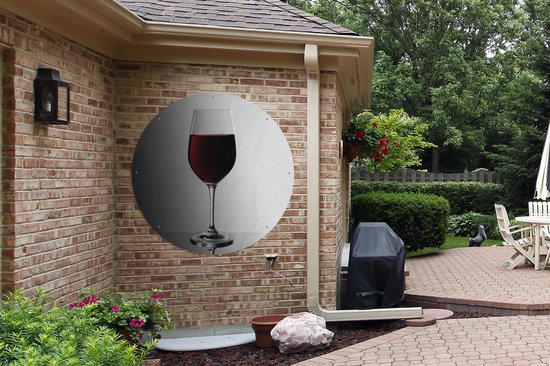 Rond tuinposter met glas rode wijn op grijs witte achtergrond, hangend aan bakstenen muur.