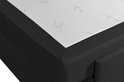 Detail van een zwart boxspringbed met wit matras, geborduurd met sierlijke lianen.