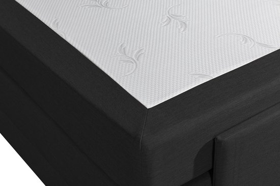 Detail van een zwart boxspringbed met wit matras, geborduurd met sierlijke lianen.