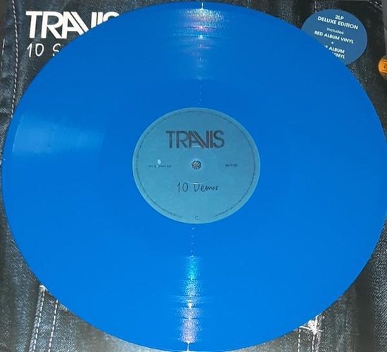 Blauw vinyl met het Travis logo en '10 Demos' op de label. De achtergrond is een spijkerbroek.
