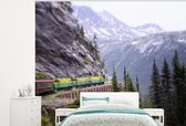 Behang - Fotobehang Een trein rijdend langs een bergwand - Breedte 275 cm x hoogte 220 cm