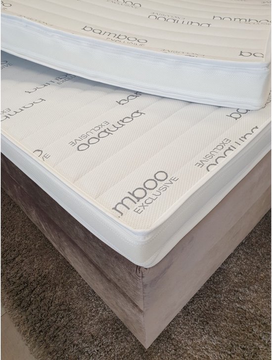 Twee witte matrassen met bamboe exclusieve opdruk, op een taupe bedbodem.