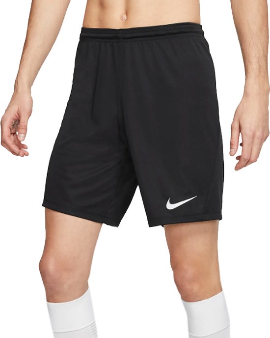 Homme portant un short de sport Nike noir avec un logo Nike blanc sur la jambe gauche et des chaussettes de sport blanches.