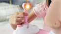 Een kinderhandje drukt op de roze douchekop met hartvormige lamp die oplicht.