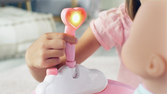 Een kinderhandje drukt op de roze douchekop met hartvormige lamp die oplicht.