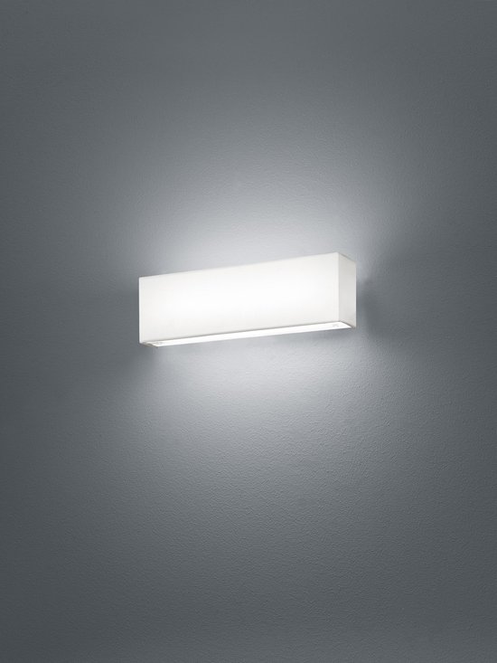 Moderne, rechthoekige wandlamp met witte stoffen kap, gemonteerd op een grijze muur. Verlicht de omgeving warm.